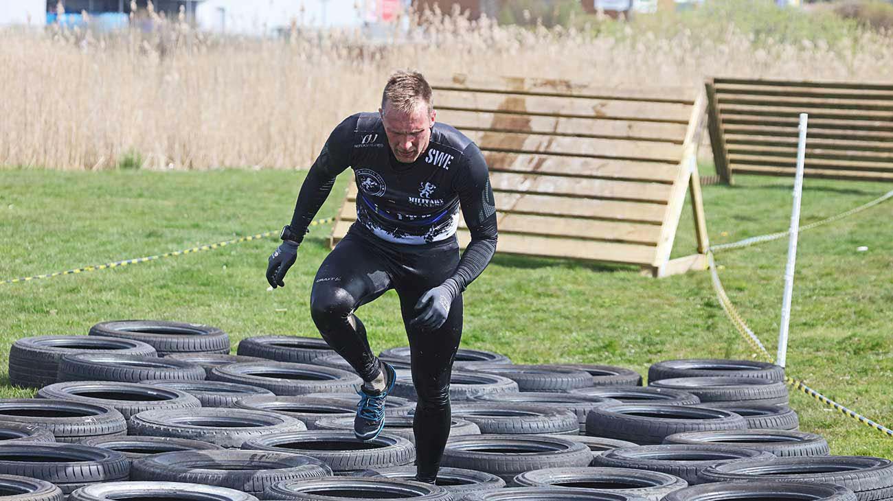 En man som springer genom ett hinder som består av massor av däck. 